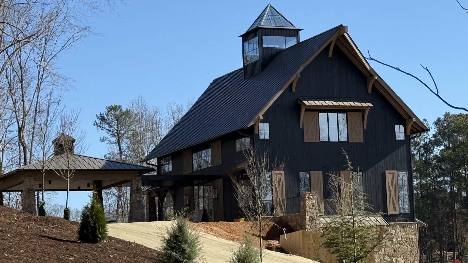 Black barn home clad in charred wood with a standing seam roof and heavy timber bracing
