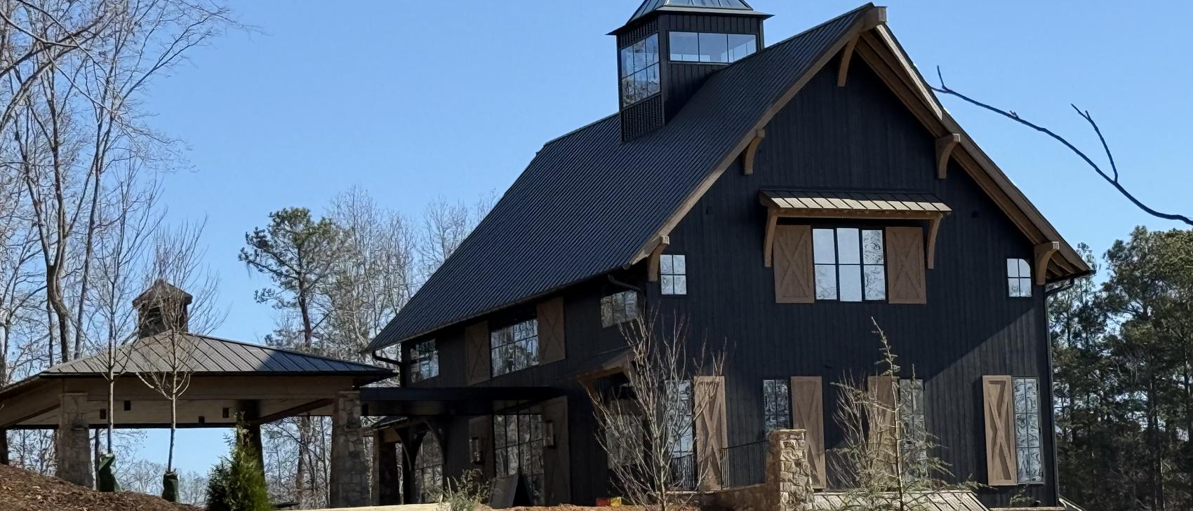 Black barn home with standing seam roof and dark gutter line