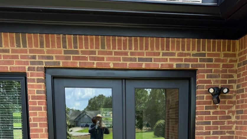 Black seamless gutter and fascia above a brick wall and composite deck