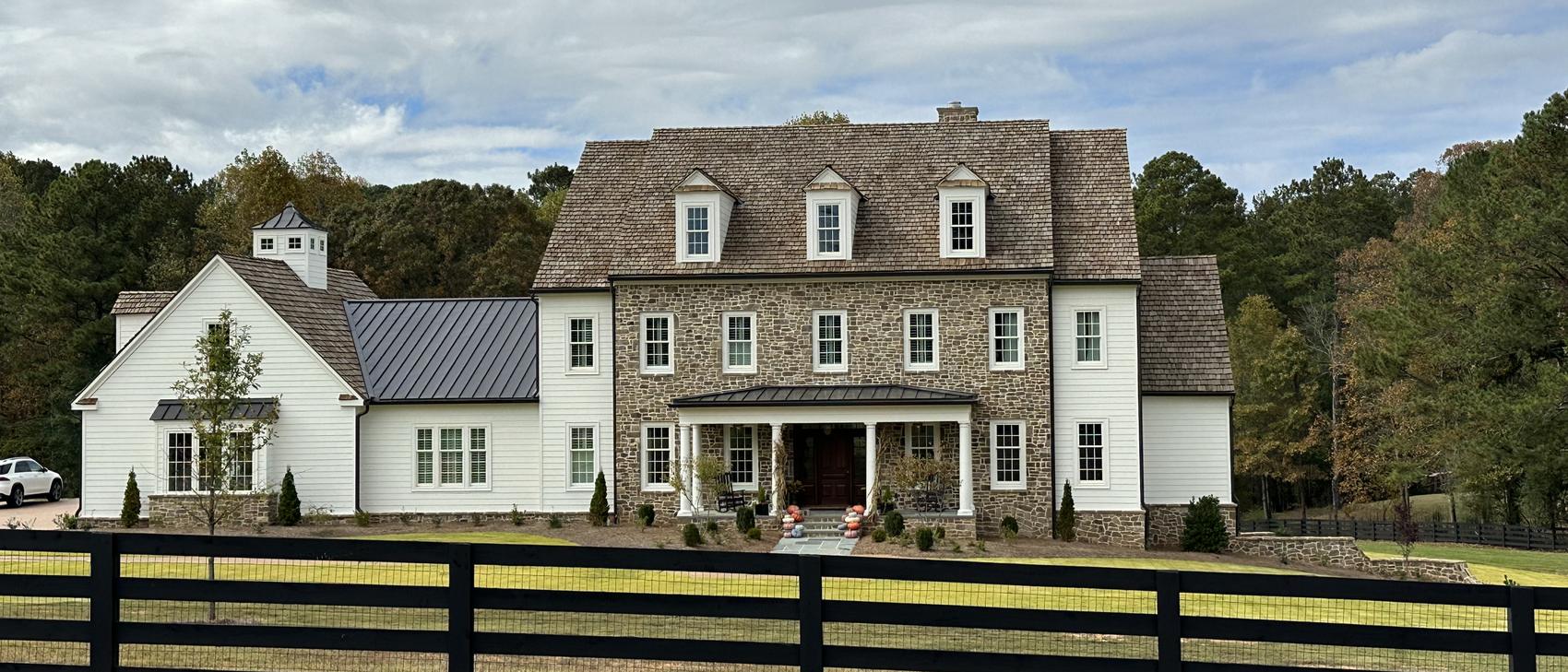Stone and lap siding home with a cedar shake roof and standing seam metal wing