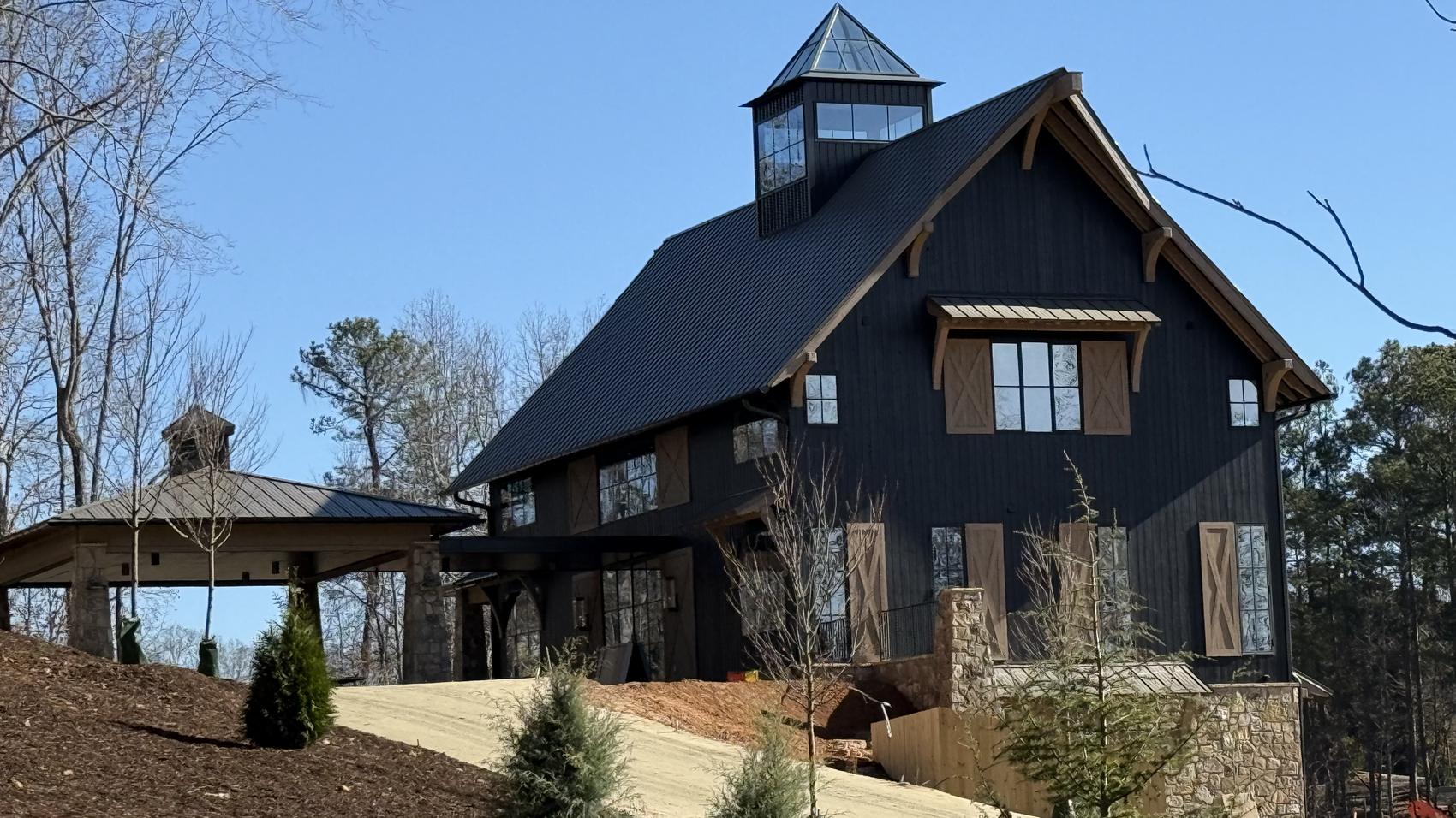 Black barn home clad in charred wood with a standing seam metal roof and cupola