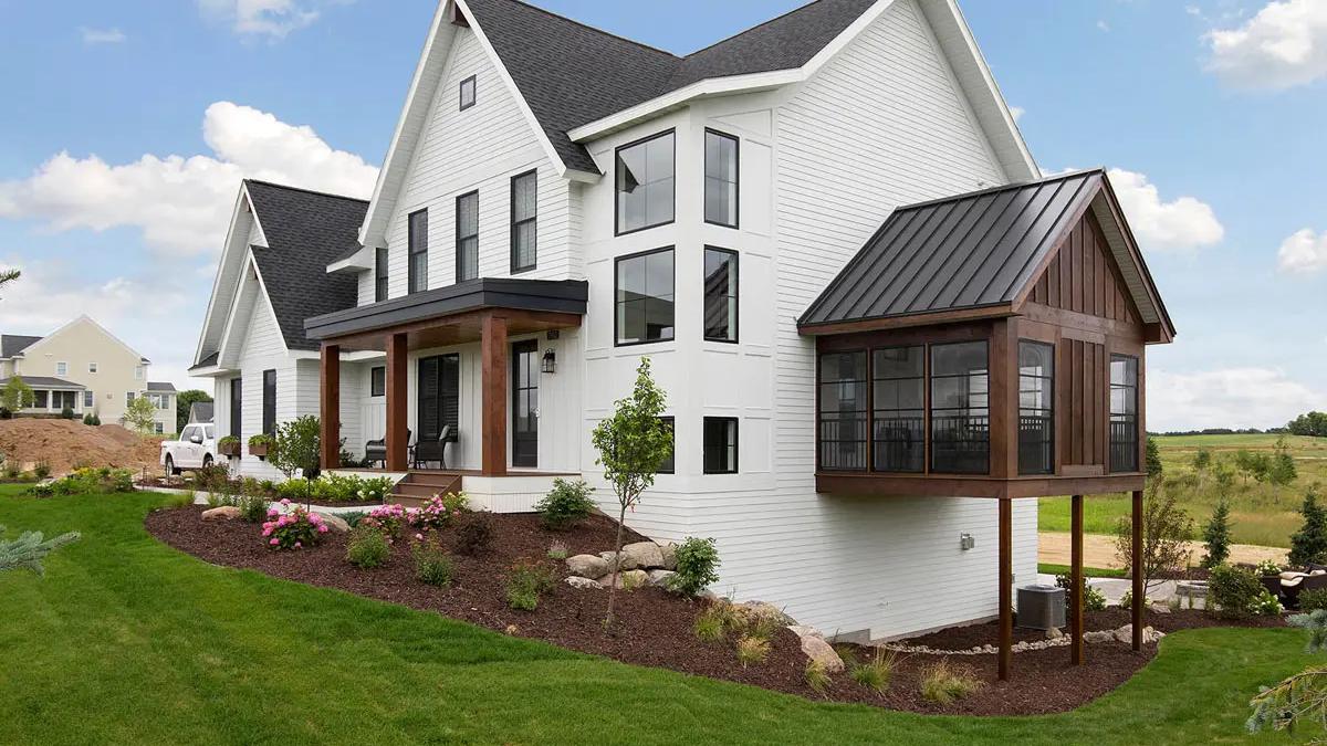 White lap siding farmhouse with board and batten gable and stained timber porch columns