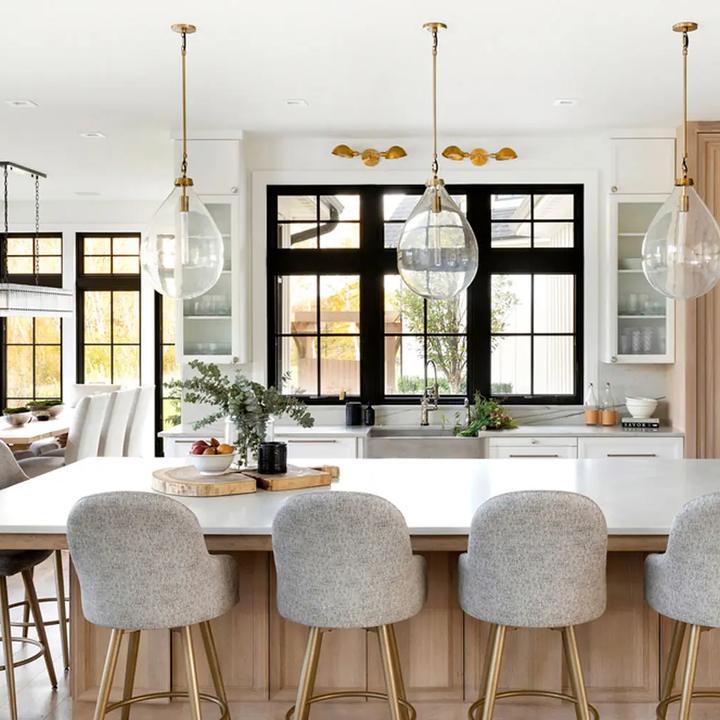 Kitchen with black-framed windows, oak island, and brass pendants