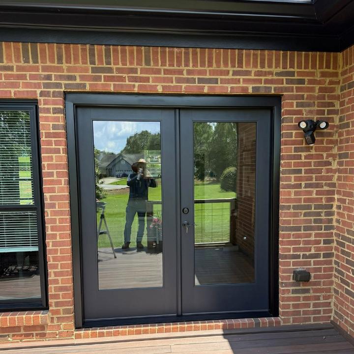 Black French doors set into red brick beside a composite deck