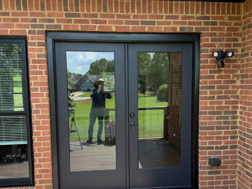 Black French doors set into red brick opening onto a composite deck